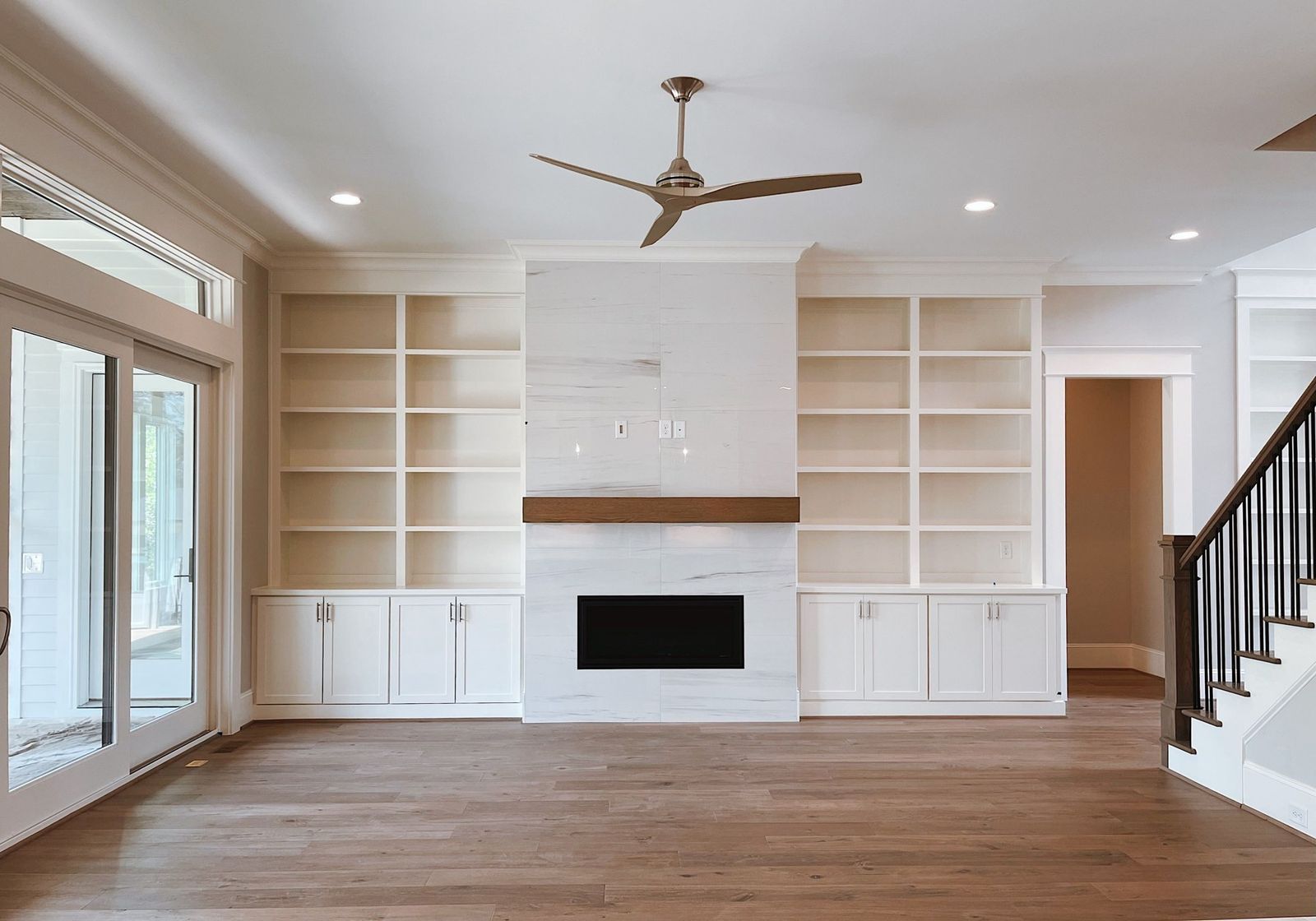 Built-in shelving and cabinets on both sides of a fireplace in a bright living room (example style photo)