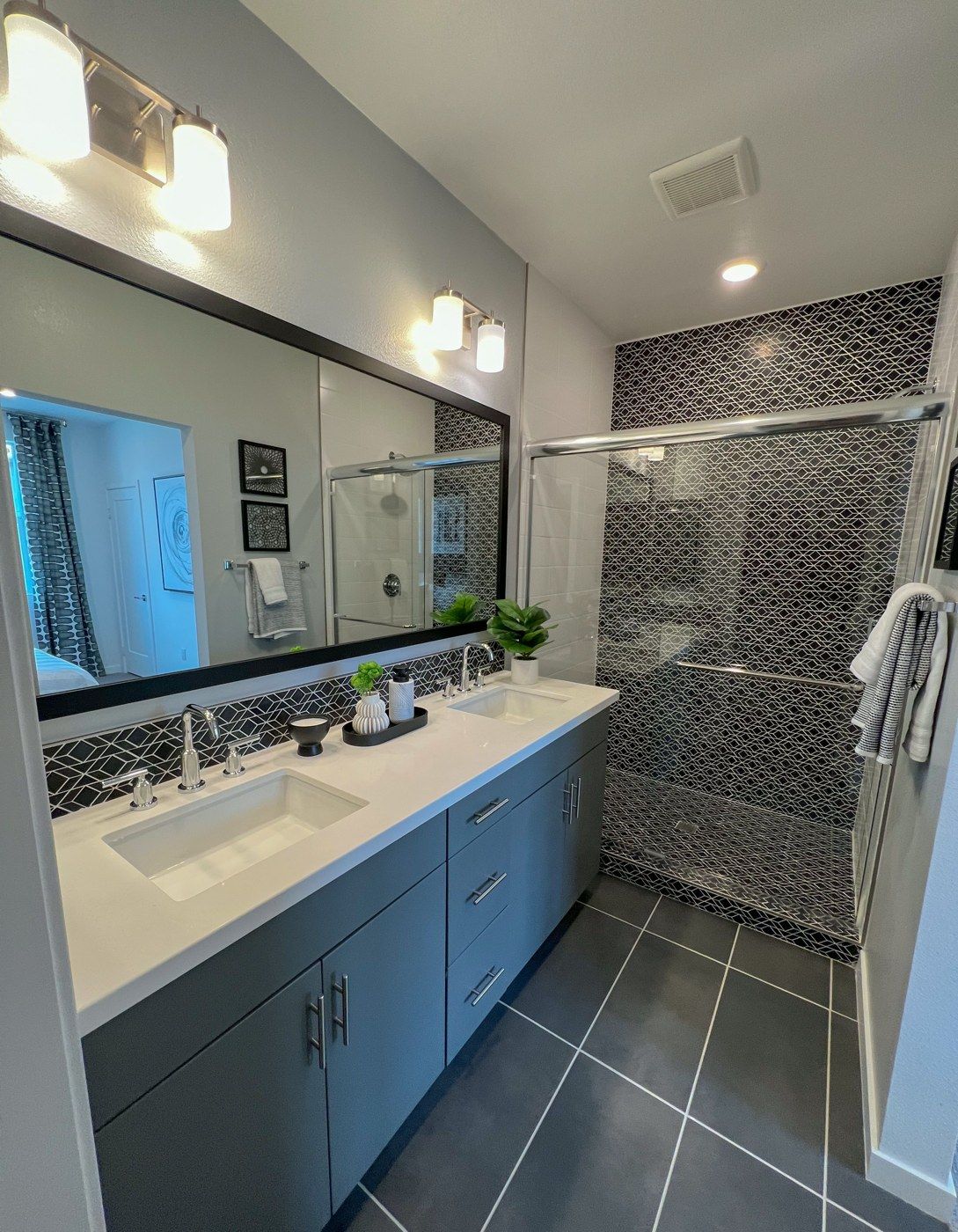 Gray double-sink bathroom vanity beside a tiled walk-in shower (example style photo)